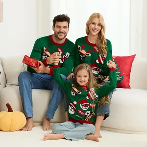 Familia feliz con jerséis navideños verdes a juego con motivos de renos y Papá Noel