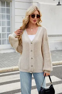 Outdoor shot of a stylish woman wearing a beige V-neck cable knit cardigan sweater.