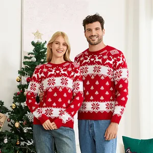 Man and woman wearing festive red Christmas sweaters with white reindeer jacquard patterns.