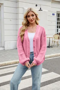 Detail showing the fit of a pink V-neck cable knit cardigan on a model outdoors
