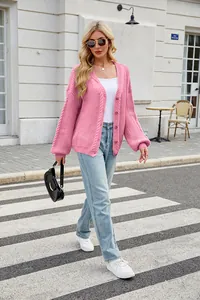 Pink chunky knit cardigan with V-neck and oversized fit shown in a street setting