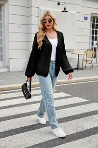 Blonde woman wearing a black chunky cable knit cardigan with jeans on street crosswalk