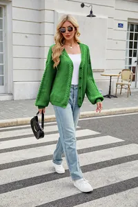 Fashionable women's green oversized cable knit cardigan shown on a European street backdrop