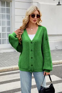 Detail shot of a vibrant green oversized V-neck cable knit cardigan worn by a blonde model