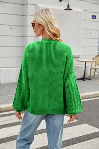 Back view of a vibrant green chunky knit oversized sweater in a street style setting.