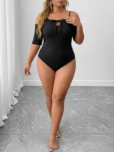 Detail view of a black ribbed plus-size bodysuit with off-the-shoulder tie neck