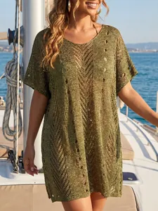 Close-up of green metallic crochet beach cover-up on a sunlit boat deck by the sea.