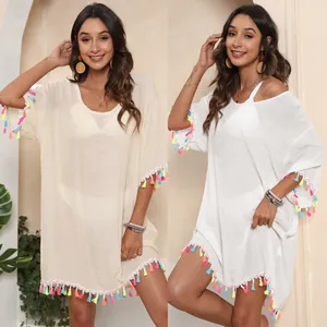 Détail de robe de plage ample avec pompons colorés en blanc et beige