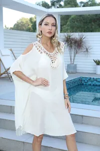 Detail of crochet patchwork neckline on loose white cold-shoulder beach cover-up