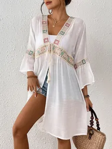 Detail des weißen Strand-Cover-ups mit bunten Paillettenstickereien und Spitze
