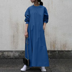 Full-length shot of a loose-fit blue long-sleeved maxi dress styled with white sneakers