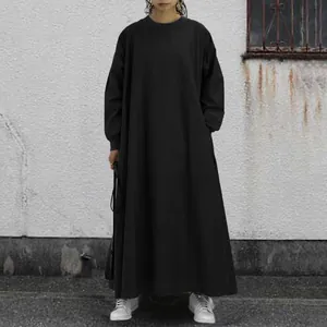Model wearing a loose black long-sleeved maxi dress in an urban outdoor setting