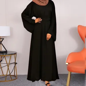 Close-up full view of black modest maxi dress with wide sleeves shown in a modern interior setting