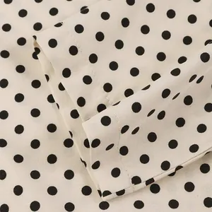 Detailed close-up of beige polka dot dress fabric showing high-quality stitching and texture