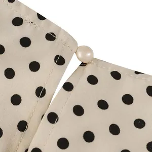 Close-up detail showing the elegant pearl button and classic polka dot fabric on a dress