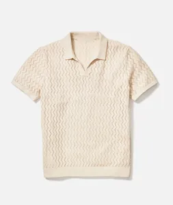 Close-up of men's cream hollow-knit short-sleeved polo shirt showing texture.