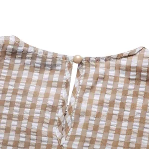 Close-up of the elegant pearl button closure on the back of a brown gingham dress