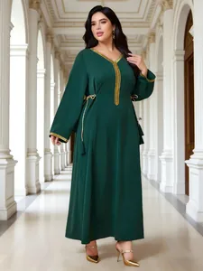 Κομψό plus size σμαραγδί μάξι φόρεμα με χρυσό τελείωμα σε κλασικό αρχιτεκτονικό διάδρομο