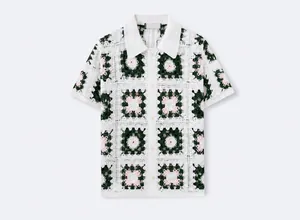 Κοντινή όψη πλεκτή ανδρική μπλούζα Polo με χειροποίητο φλοράλ σχέδιο σε λευκό και πράσινο.