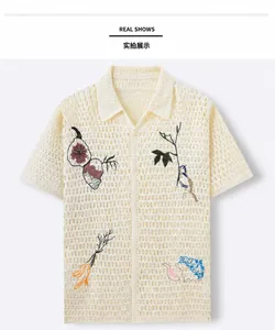 Detail of cream crochet knit polo shirt with intricate bird and fruit embroidery