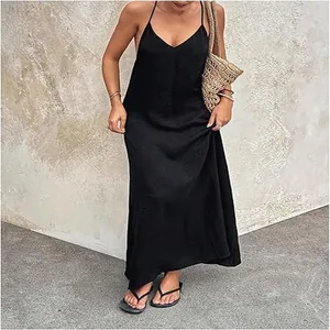 Elegante zwarte mouwloze maxi-jurk met V-hals en een rieten tas in een zomerse setting.