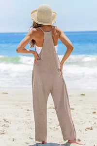 Back view of a casual brown sleeveless jumpsuit and straw hat on a sunny beach background