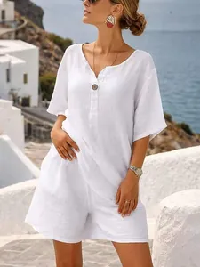 Model draagt een witte katoenen linnen zomerset tegen een prachtig uitzicht op zee.