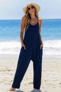 Navy blue women's spaghetti strap harem jumpsuit with large pockets on beach setting