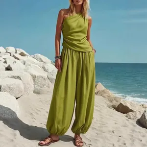 Dames tweedelige set met groene one-shoulder top en losse harembroek op het strand