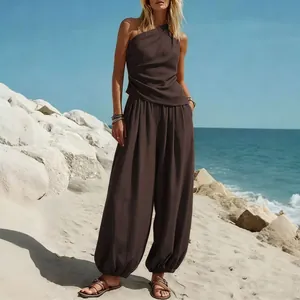 Elegant donkerbruin setje met one-shoulder top en pofbroek gedragen op een zonnig strand