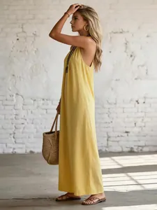 Side view of a yellow linen cotton sleeveless backless maxi dress in a holiday style.