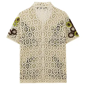 Vista dettagliata del motivo a maglia crochet traforata su polo color crema da uomo.