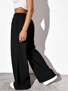 Side view of black high-waisted textured wide-leg trousers showing drape and fabric detail.