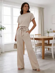 Elegant women's beige short sleeve top and high waist wide leg pants casual set in a bright room.