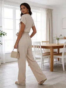 Back view of a beige short-sleeve wide-leg jumpsuit in a bright modern dining room.
