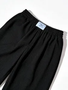 Detail shot of black high-waisted pleated wide-leg pants with textured fabric