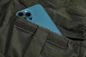 Detail of a dark green multi-pocket utility vest showing a functional velcro pocket.