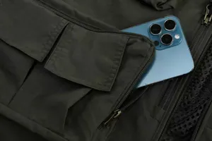 Close-up of a military green cargo fishing vest with a large zippered pocket and phone.