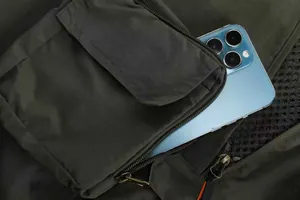 Detail of outdoor utility fishing vest showing a large zipper pocket holding a smartphone