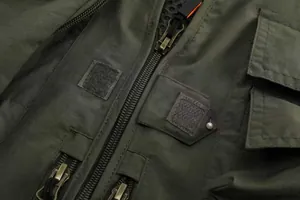 Detailed macro view of an olive green tactical fishing vest with multiple pockets and zippers.