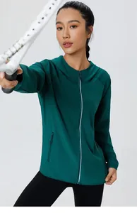 Détail d'un coupe-vent de sport vert avec poches zippées et détails réfléchissants