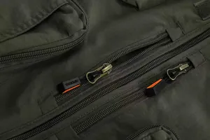 Close-up of durable metal zippers on a dark green multi-pocket outdoor fishing vest