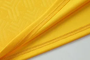 Close-up of yellow breathable soccer jersey fabric showing quality double stitching