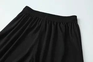 Detail view of the elastic waistband and breathable mesh fabric on black soccer shorts.