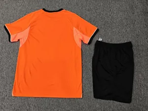 Back view of orange short-sleeve soccer jersey and black shorts on gray carpet