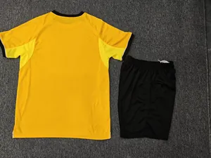 Detailed view of yellow soccer jersey and black shorts set on gray background.