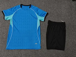Detail view of blue soccer jersey and black shorts set laid flat on gray surface