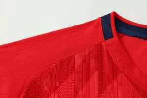 Close-up of breathable jacquard fabric on a red soccer jersey with blue collar detail.