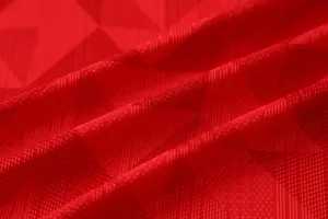 Detailed view of breathable red jacquard fabric for soccer jerseys with geometric pattern