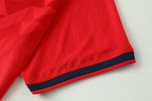 Close-up of red soccer jersey sleeve showing breathable jacquard fabric and navy cuff.